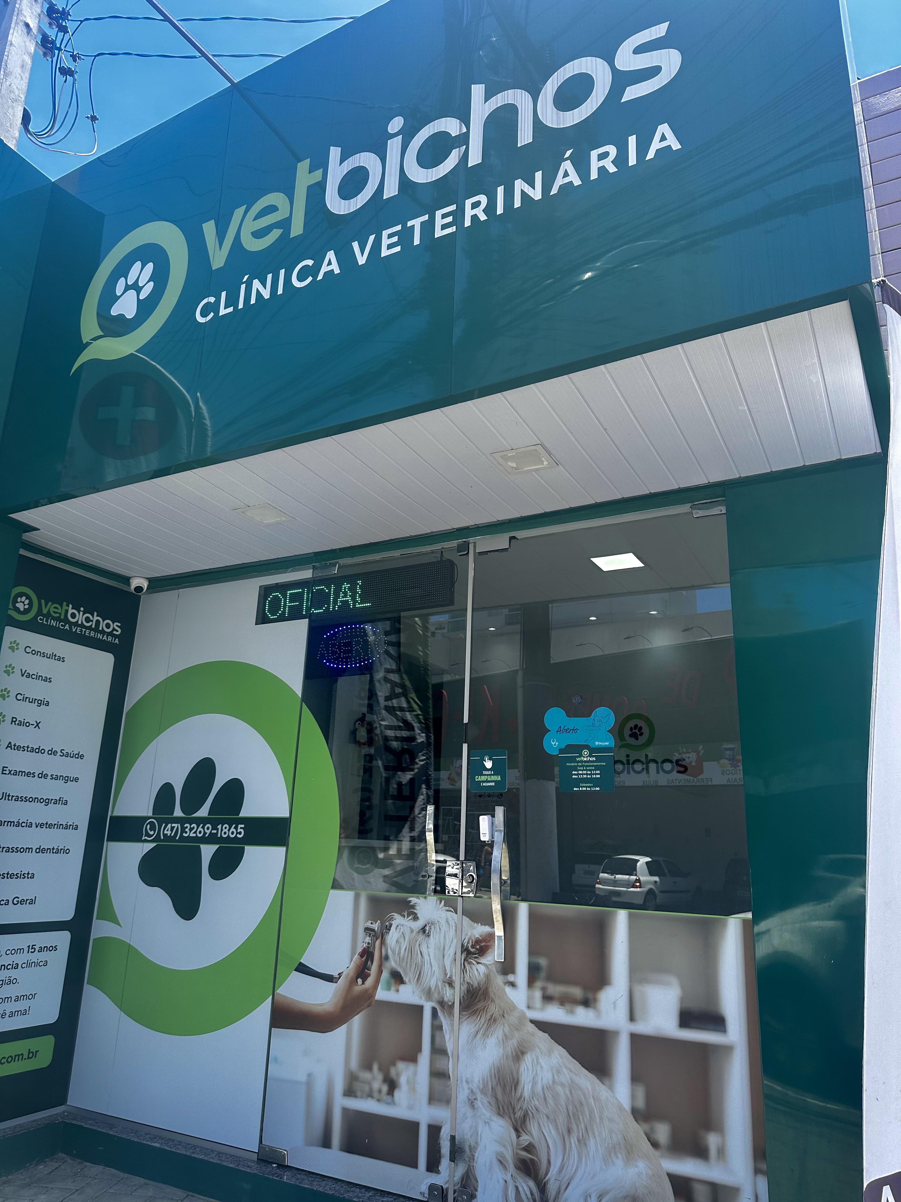 Fachada da Clínica Veterinária Vetbichos em Itapema-SC com cachorro branco na entrada, mostrando os serviços oferecidos